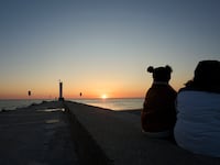 People gather near the pier in Grand Bend, Ontario, to watch the sunset over Lake Huron on May 12, 2024.