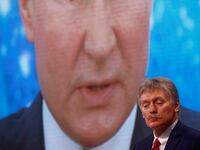 Kremlin spokesman Dmitry Peskov in front of an electronic screen showing Vladimir Putin