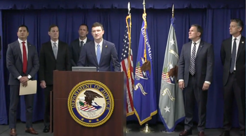 A group of similar looking white men in front of flags