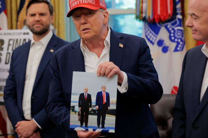 WASHINGTON, DC - AUGUST 22: U.S. President Donald Trump holds a photograph of him with Russian President Vladimir Putin in Alaska in the Oval Office August 22, 2025 in Washington, DC. Trump announced the FIFA World Cup 2026 draw will take place at The Kennedy Center. (Photo by Chip Somodevilla/Getty Images)