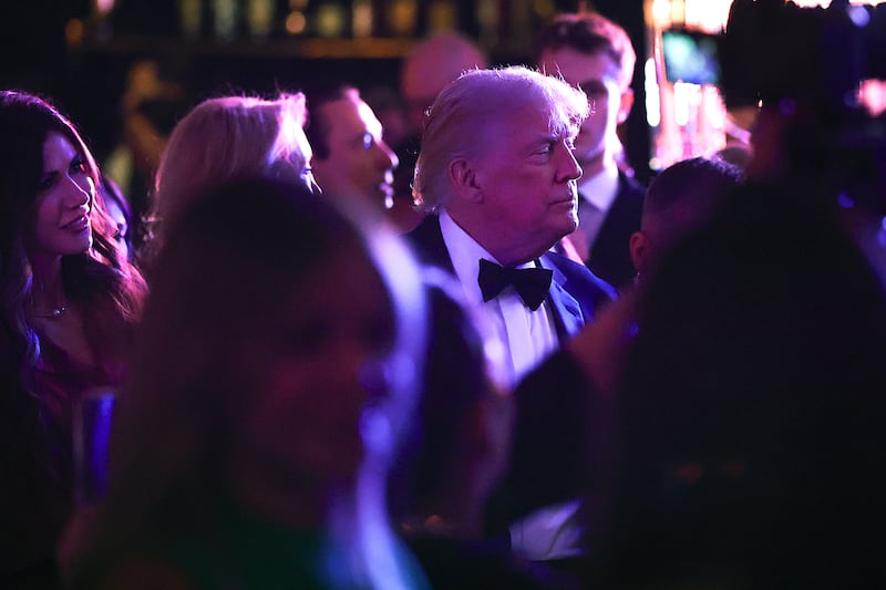 Donald Trump mingles with guests while "ICE Barbie" Kristi Noem looks on at the president's New Year's Eve party at Mar-a-Lago.