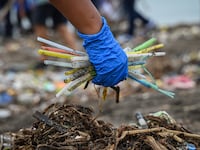 A volunteer holds discarded plastic waste, including straws, as she participates in International Coastal Cleanup Day along Baseco Beach in Manila on September 21, 2024.