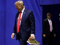Former President Donald Trump holding a pair of gold Trump-branded shoes