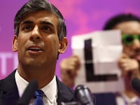 Independent candidate Niko Omilana holds an "L" behind Britain's Prime Minister and Conservative Party leader Rishi Sunak as he delivers a speech after retaining his seat as MP for Richmond and Northallerton in Northallerton, early on July 5, 2024.