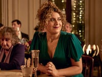Rose Matafeo sitting at a table in a green dress at a wedding in ‘Starstruck’