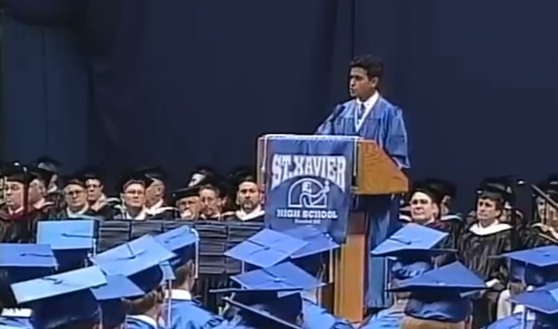 Vivek Ramaswamy in academic robes addressing a crowd of people also in academic dress.