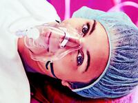 A photo illustration of a patient with respiratory mask awake on operating room table.