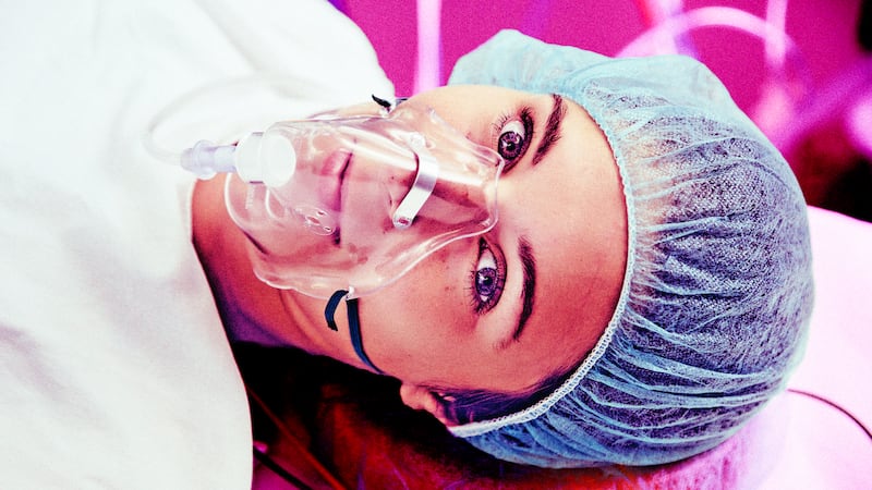 A photo illustration of a patient with respiratory mask awake on operating room table.