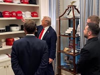 Trump shows Zelensky and Macron his trolling MAGA hat collection at Ukraine White House summit.