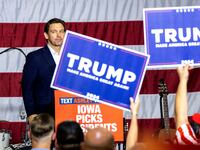 Republican U.S. presidential candidate and Florida Governor Ron DeSantis looks into the crowd after speaking as supporters of former President Donald Trump hold up signs.