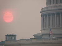 The sun rises behind the U.S. Capitol building during a summer heat wave as smoke from wildfires in Canada fills the air