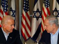 Then-U.S. Vice President Joe Biden sits with Israel's Prime Minister Benjamin Netanyahu before flags