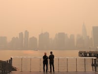 "People watch the sunset as haze and smoke caused by wildfires in Canada hang over the Manhattan skyline.