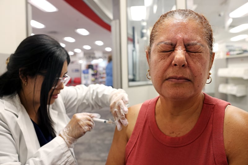 HUNTINGTON PARK-CA-AUGUST 28, 2024: Elizabeth Gomez, 54, of Huntington Park, right, receives a Prevnar and shingles vaccine by pharmacy manager Sandra Gonzalez at CVS in Huntington Park on August 28, 2024. (Christina House / Los Angeles Times via Getty Images)