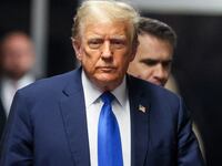 Donald Trump, wearing a suit, walks into court with a stoic look on his face.